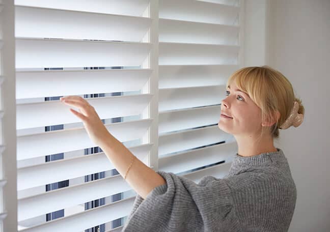 photo of a woman inspecting a new looking shutters